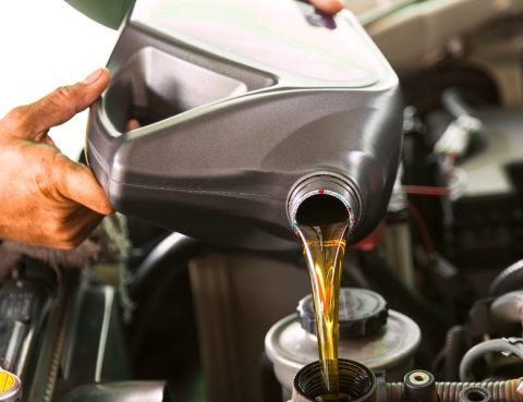 Man pouring motor oil into car