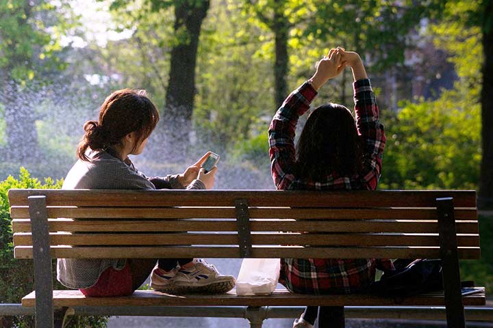 2 girls resting on a park bench