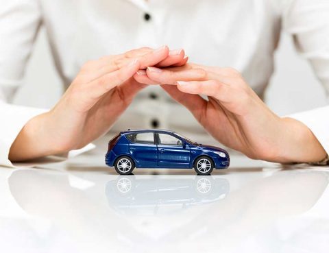 Hands covering a toy SUV to illustrate warranty coverage