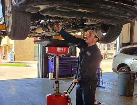 Certified mechanic at a non-dealer repair shop performing an oil change