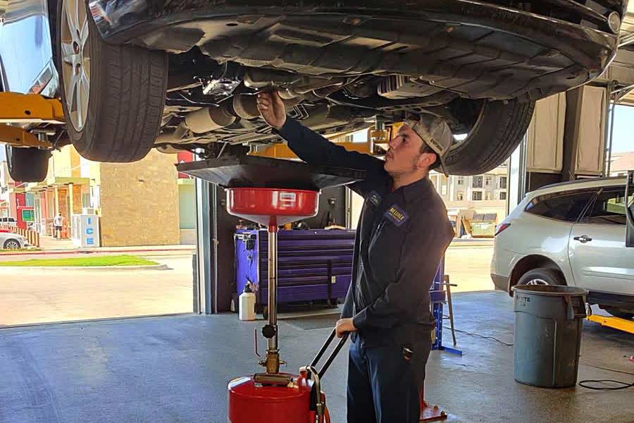 Certified mechanic at a non-dealer repair shop performing an oil change