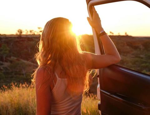 Woman exiting a truck to watch the sun rise on a summer road trip