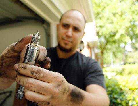 Auto mechanic holding a new spark plug for demonstration