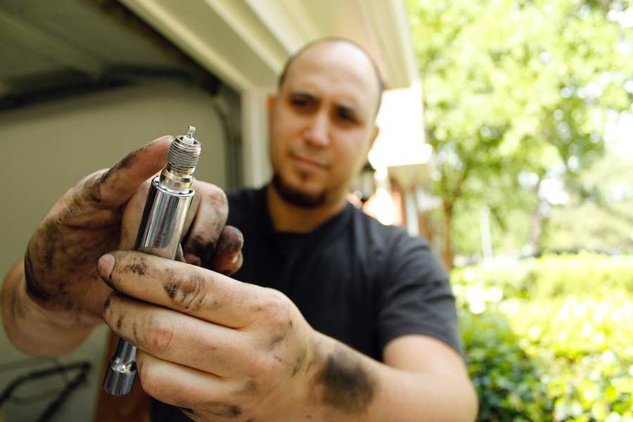Auto mechanic holding a new spark plug for demonstration