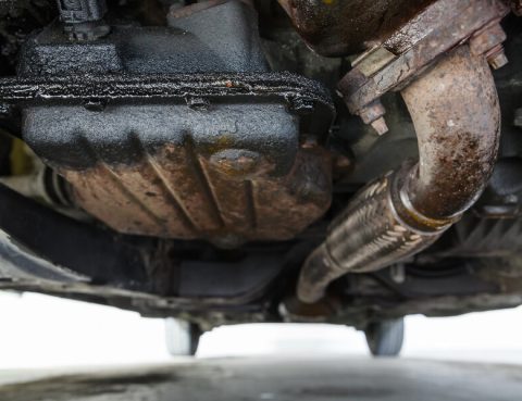 Close-up of the underside of a car, showing an engine oil leak.