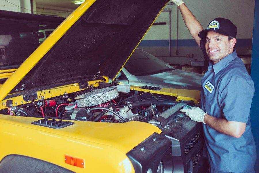 friendly neighborhood mechanic doing repairs on a yellow vehicle - Automotive Shop for Fast Auto Repair & Oil Change in San Marcos, Kyle, and Buda, Tx