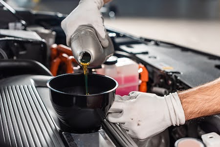 mechanic pouring engine oil into funnel during a service